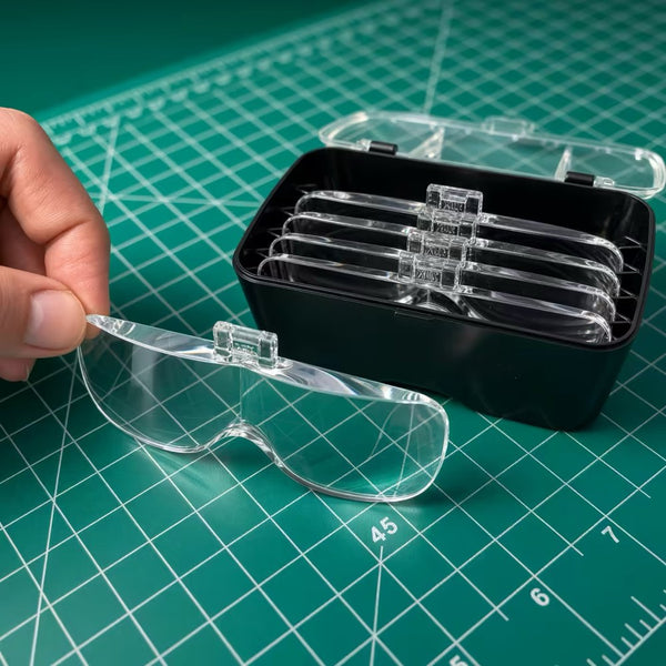 A hand lifting one clear VisionAid lens out of the lens case, with the other four lenses standing in their slots